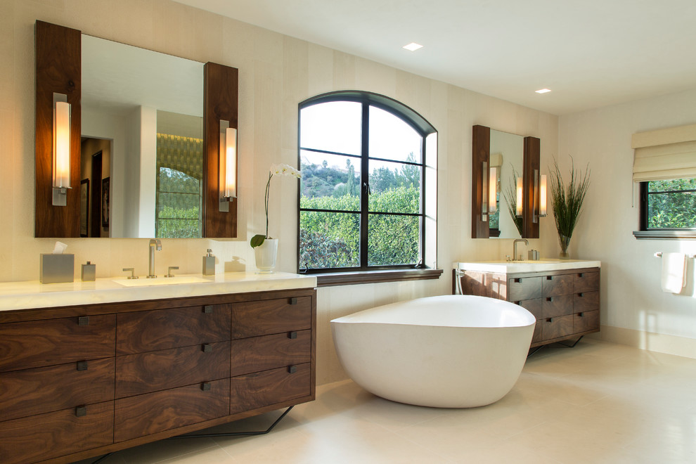 Свежая идея для дизайна: большая главная ванная комната в современном стиле с плоскими фасадами, темными деревянными фасадами, отдельно стоящей ванной, белыми стенами, полом из керамогранита и врезной раковиной - отличное фото интерьера