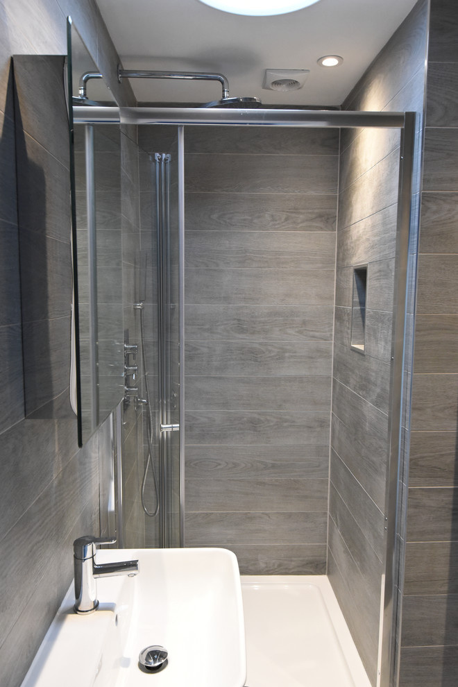 Réalisation d'une salle de bain principale minimaliste de taille moyenne avec une douche à l'italienne, WC à poser, un carrelage gris, des carreaux de céramique, un mur gris, un sol en carrelage de céramique et un lavabo suspendu.