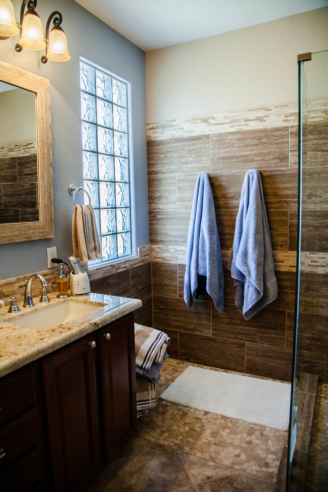 Example of a mid-sized transitional ceramic tile corner shower design in Phoenix with dark wood cabinets, blue walls, an undermount sink, granite countertops and raised-panel cabinets