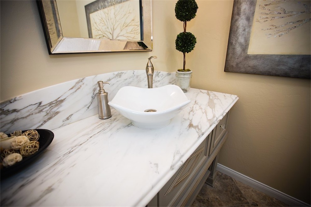 Klassisk inredning av ett badrum, med ett fristående handfat, möbel-liknande, grå skåp, marmorbänkskiva, en toalettstol med separat cisternkåpa, brun kakel, porslinskakel, beige väggar och klinkergolv i porslin
