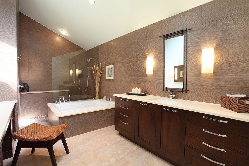 Photo of a large traditional ensuite bathroom in Miami with shaker cabinets, dark wood cabinets, a corner bath, a shower/bath combination, brown walls, ceramic flooring, a submerged sink, limestone worktops, beige floors, a hinged door and beige worktops.