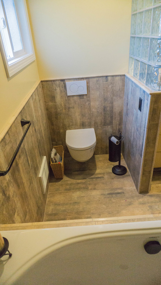Idéer för att renovera ett mellanstort eklektiskt en-suite badrum, med släta luckor, skåp i ljust trä, ett platsbyggt badkar, en vägghängd toalettstol, gula väggar, klinkergolv i porslin, ett undermonterad handfat och marmorbänkskiva