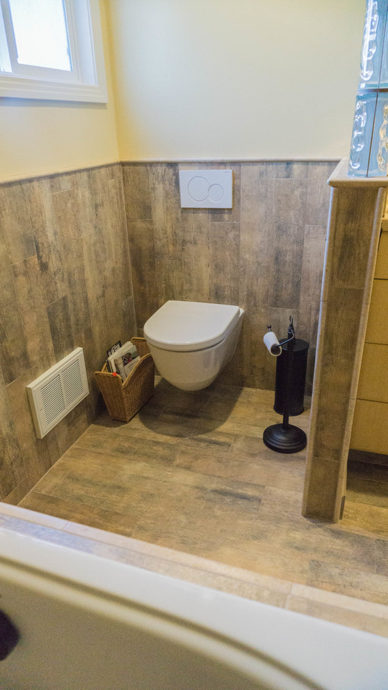 Réalisation d'une salle de bain principale bohème en bois clair de taille moyenne avec un placard à porte plane, une baignoire posée, WC suspendus, un mur jaune, un sol en carrelage de porcelaine, un lavabo encastré et un plan de toilette en marbre.