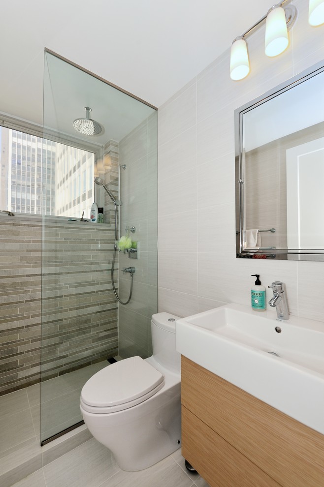 Inspiration for a small contemporary bathroom in New York with an integrated sink, flat-panel cabinets, light wood cabinets, solid surface worktops, a corner shower, a one-piece toilet, white tiles, ceramic tiles, white walls and ceramic flooring.