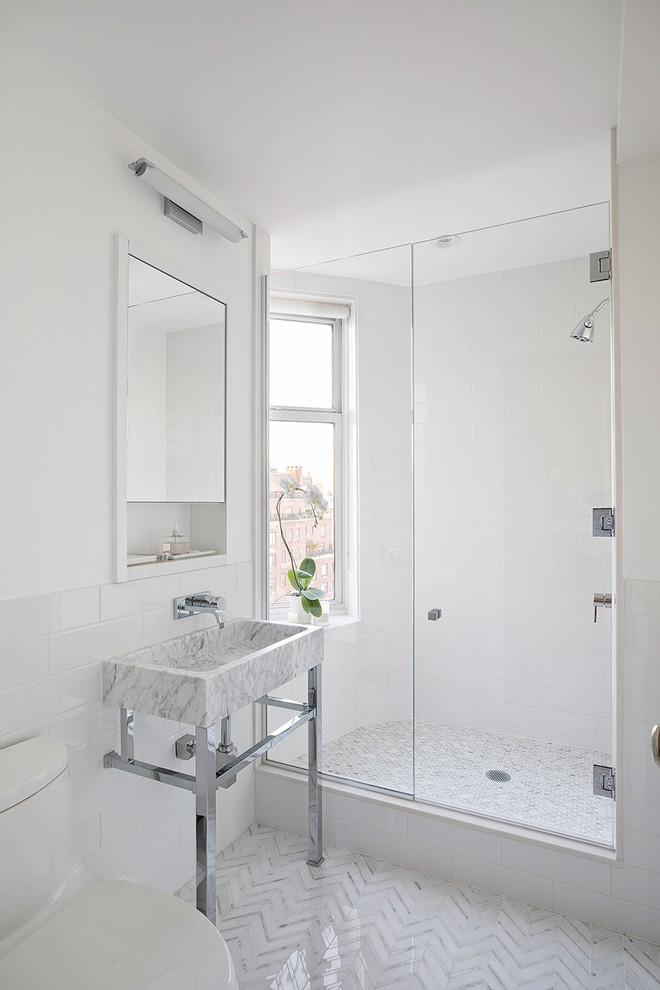 Foto på ett litet vintage badrum med dusch, med en dusch i en alkov, en toalettstol med hel cisternkåpa, grå kakel, vit kakel, stenkakel, vita väggar, marmorgolv, ett konsol handfat och dusch med gångjärnsdörr