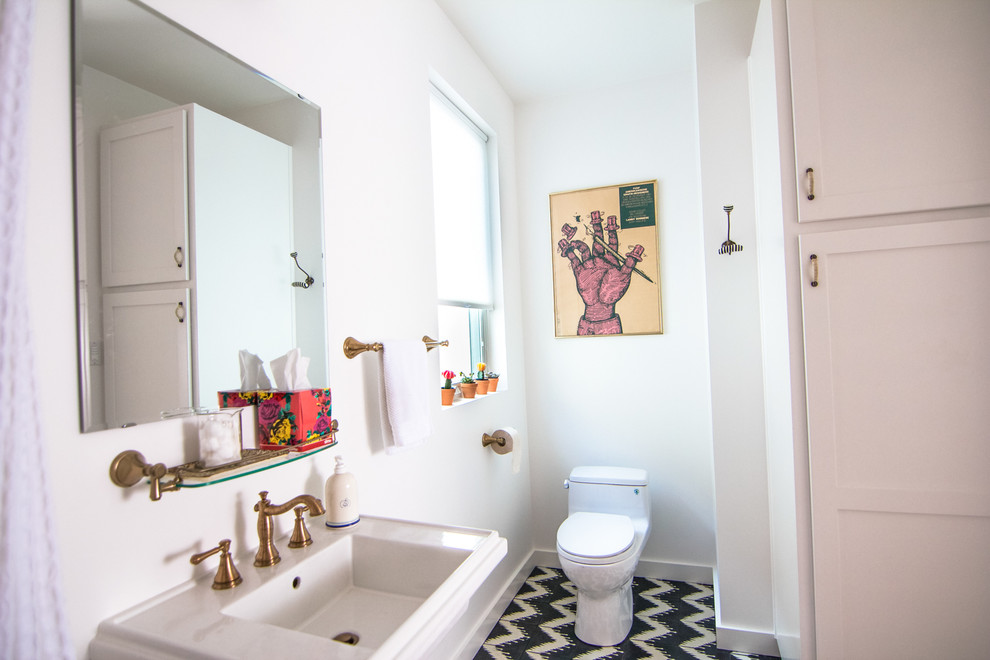 Inspiration pour une petite salle de bain vintage avec un placard à porte shaker, des portes de placard blanches, WC à poser, un carrelage noir et blanc, des carreaux de béton, un mur blanc et un plan de toilette en verre.