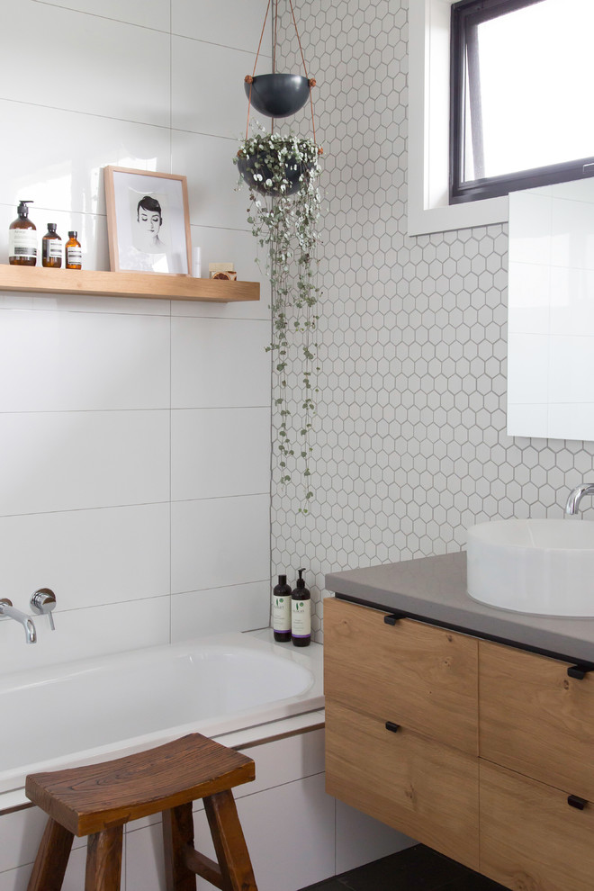 Inspiration för mellanstora moderna vitt en-suite badrum, med släta luckor, skåp i mellenmörkt trä, en dusch/badkar-kombination, grå kakel, vit kakel, keramikplattor, vita väggar, klinkergolv i keramik, ett fristående handfat, bänkskiva i betong och grått golv
