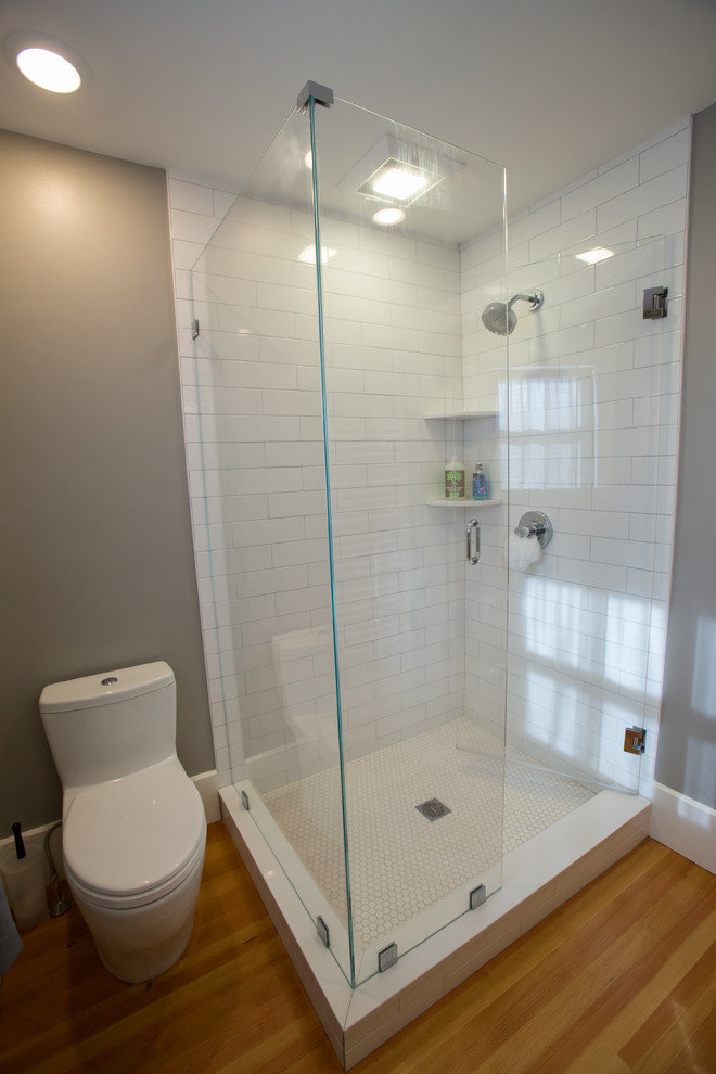 Corner shower - mid-sized contemporary 3/4 white tile and subway tile medium tone wood floor and brown floor corner shower idea in Boston with flat-panel cabinets, medium tone wood cabinets, a one-piece toilet, brown walls, an integrated sink, solid surface countertops and a hinged shower door