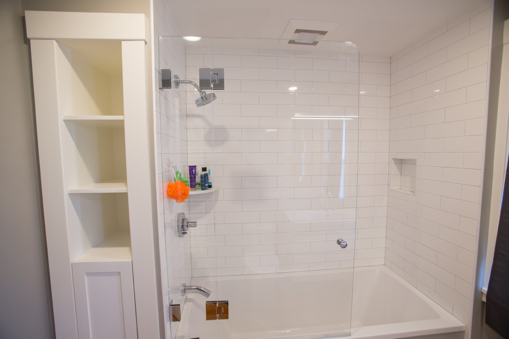 Photo of a small contemporary ensuite bathroom in Boston with flat-panel cabinets, white cabinets, an alcove bath, an alcove shower, a one-piece toilet, white tiles, metro tiles, grey walls, medium hardwood flooring, an integrated sink, solid surface worktops, brown floors and a sliding door.