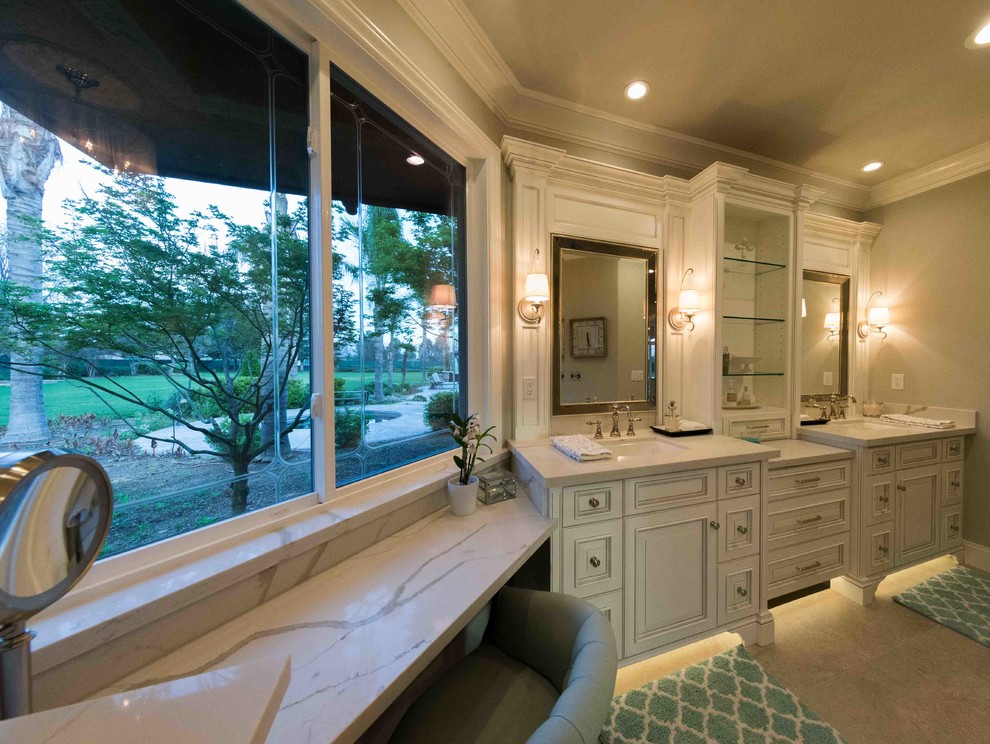 Inspiration for a large transitional master beige tile double shower remodel in Other with raised-panel cabinets, white cabinets, a one-piece toilet, gray walls, an undermount sink, marble countertops, a hinged shower door and white countertops