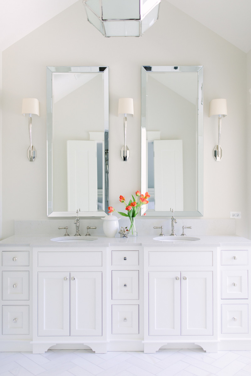 Immagine di una stanza da bagno chic con ante a filo, ante bianche, pareti beige, lavabo sottopiano e pavimento bianco