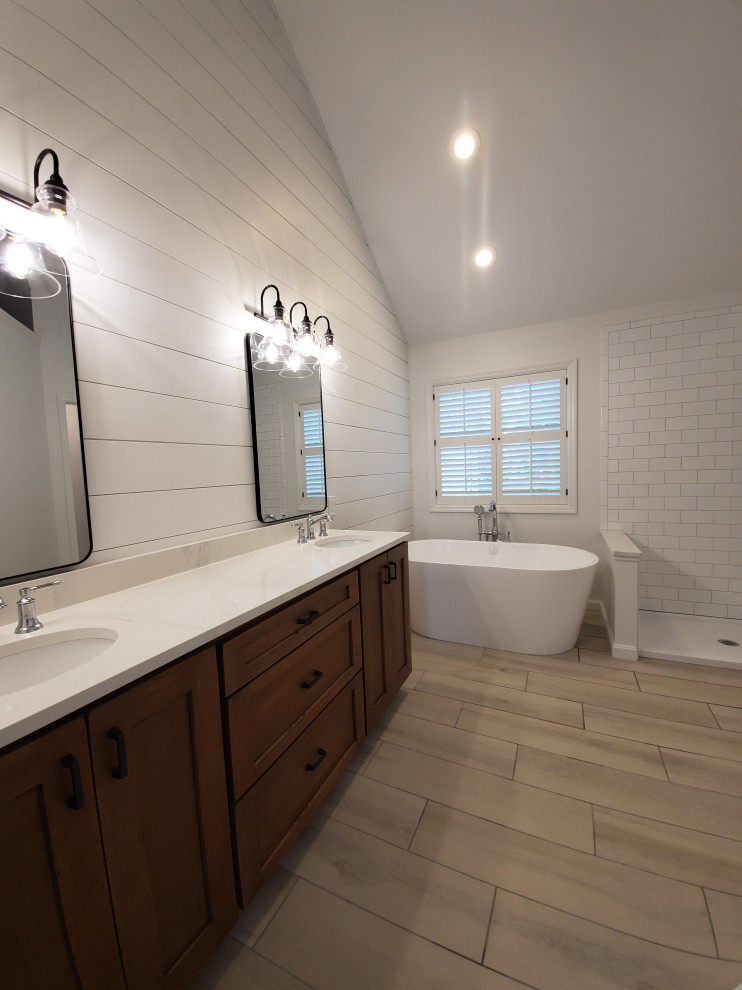 Example of a large cottage master white tile and subway tile porcelain tile and beige floor bathroom design in Cincinnati with recessed-panel cabinets, medium tone wood cabinets, a two-piece toilet, white walls, an undermount sink, quartzite countertops, a hinged shower door and white countertops