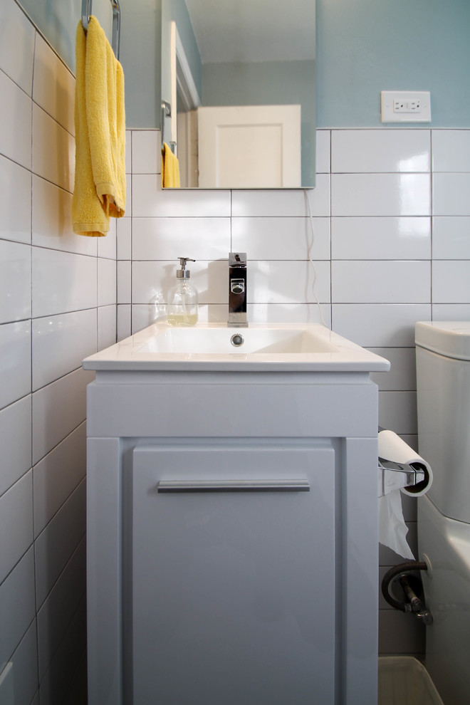 Réalisation d'une petite salle de bain principale design avec un placard à porte shaker, des portes de placard blanches, une baignoire en alcôve, un combiné douche/baignoire, WC à poser, un carrelage blanc, des carreaux de porcelaine, un mur bleu, un sol en carrelage de porcelaine, un lavabo intégré et un plan de toilette en quartz modifié.