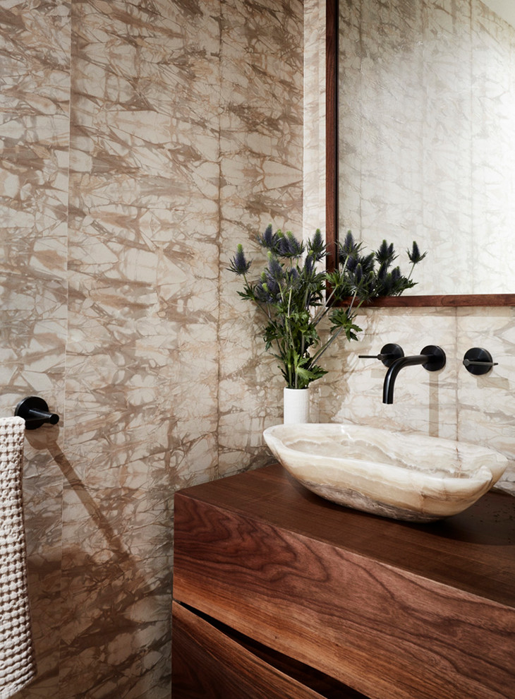 Diseño de cuarto de baño contemporáneo con armarios con paneles lisos, puertas de armario de madera oscura, paredes beige, lavabo sobreencimera, encimera de madera y encimeras marrones