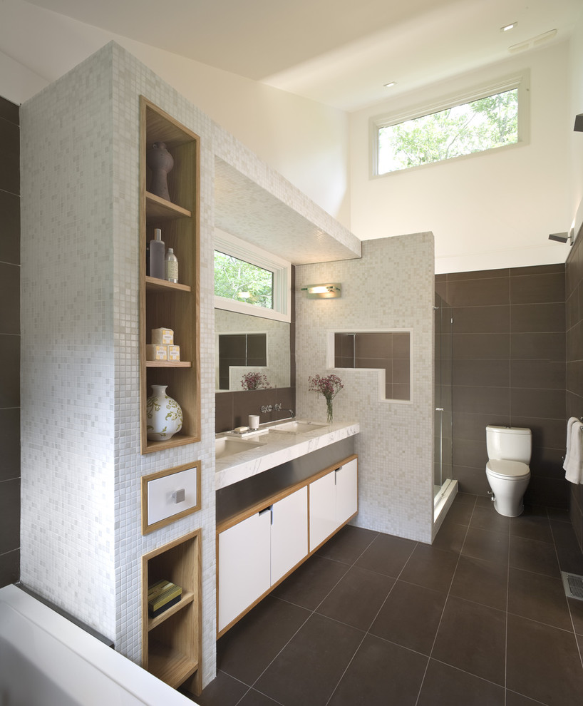 Large trendy master brown tile and stone tile limestone floor alcove shower photo in New York with an undermount sink, flat-panel cabinets, white cabinets, a two-piece toilet, marble countertops and brown walls