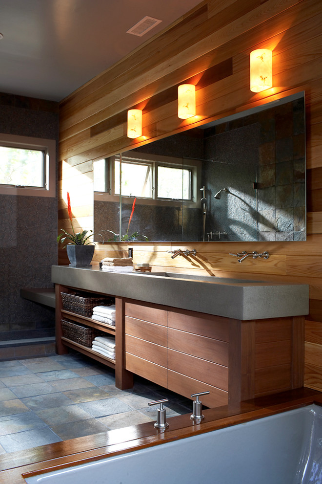 На фото: большая главная ванная комната в современном стиле с плоскими фасадами, темными деревянными фасадами, полновстраиваемой ванной, унитазом-моноблоком, коричневыми стенами, полом из сланца, раковиной с несколькими смесителями и столешницей из бетона