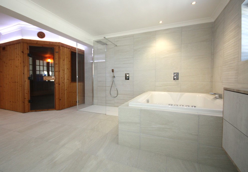 Diseño de sauna actual con jacuzzi, ducha abierta, baldosas y/o azulejos grises y ducha abierta