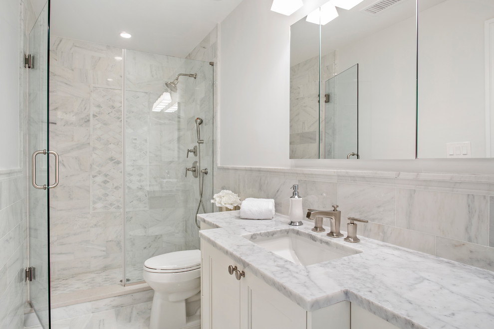 Inspiration for a traditional shower room bathroom in New York with recessed-panel cabinets, white cabinets, an alcove shower, a two-piece toilet, white tiles, marble tiles, white walls, marble flooring, a submerged sink, marble worktops and a hinged door.