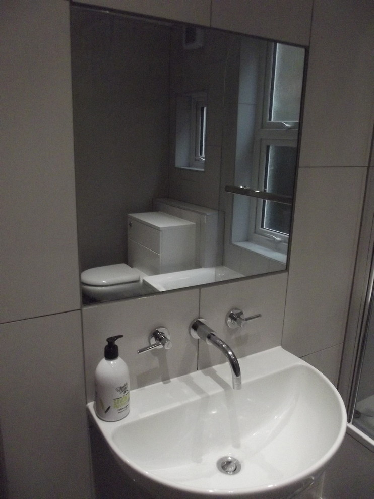 Photo of a medium sized contemporary family bathroom in London with flat-panel cabinets, white cabinets, a built-in bath, a shower/bath combination, a one-piece toilet, grey tiles, porcelain tiles, grey walls, porcelain flooring and a wall-mounted sink.