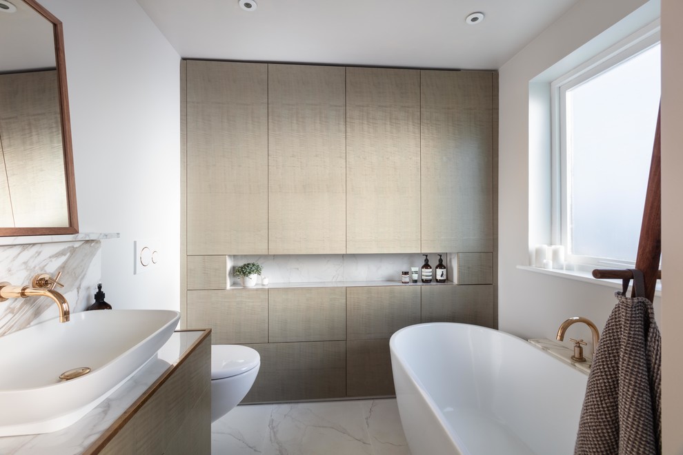 Small trendy kids' ceramic tile and gray floor freestanding bathtub photo in London with flat-panel cabinets, gray cabinets, a wall-mount toilet, marble countertops, gray countertops, white walls and a vessel sink