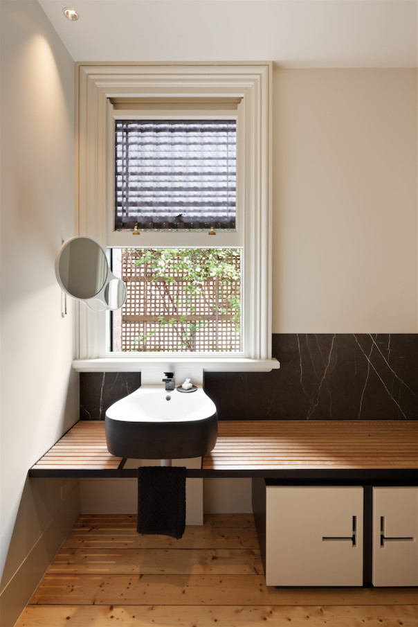 Medium sized contemporary bathroom in Melbourne with white cabinets, a corner shower, black tiles, marble tiles, white walls, light hardwood flooring, a wall-mounted sink, wooden worktops and a hinged door.
