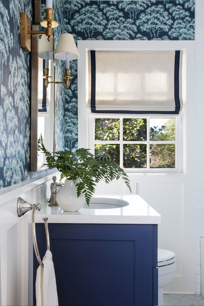 Diseño de cuarto de baño clásico renovado con armarios estilo shaker, puertas de armario azules, sanitario de dos piezas, lavabo bajoencimera, encimera de mármol, suelo blanco y encimeras blancas