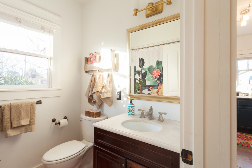 Kleines Stilmix Badezimmer mit profilierten Schrankfronten, dunklen Holzschränken, Duschbadewanne, Toilette mit Aufsatzspülkasten, weißer Wandfarbe, Unterbauwaschbecken und Mineralwerkstoff-Waschtisch in Nashville