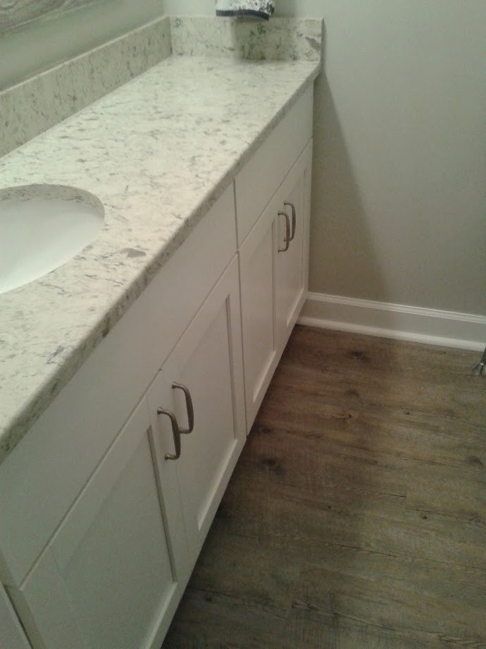 Inredning av ett klassiskt litet vit vitt badrum med dusch, med släta luckor, vita skåp, en toalettstol med separat cisternkåpa, vita väggar, mellanmörkt trägolv, ett nedsänkt handfat, laminatbänkskiva och brunt golv