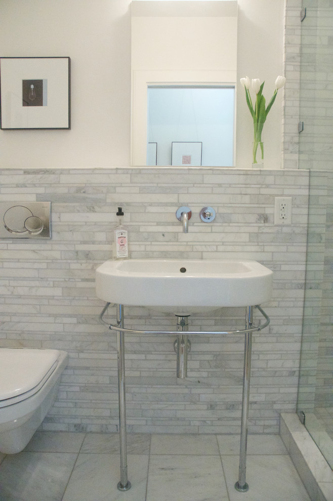 Réalisation d'une salle de bain minimaliste avec WC suspendus, du carrelage en marbre, un mur blanc, un sol en marbre, un lavabo suspendu, un sol gris et une cabine de douche à porte battante.