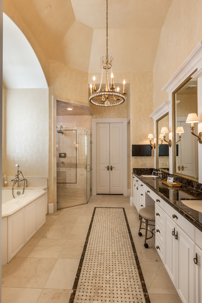 Exempel på ett klassiskt badrum, med ett undermonterad handfat, luckor med upphöjd panel, vita skåp, ett undermonterat badkar, beige kakel, beige väggar och beiget golv