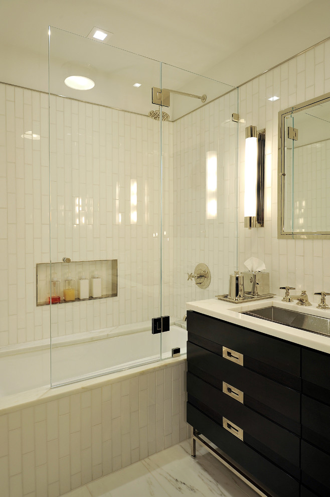 На фото: ванная комната в современном стиле с врезной раковиной, черными фасадами, полновстраиваемой ванной, душем над ванной, белой плиткой, плиткой кабанчик, нишей и плоскими фасадами