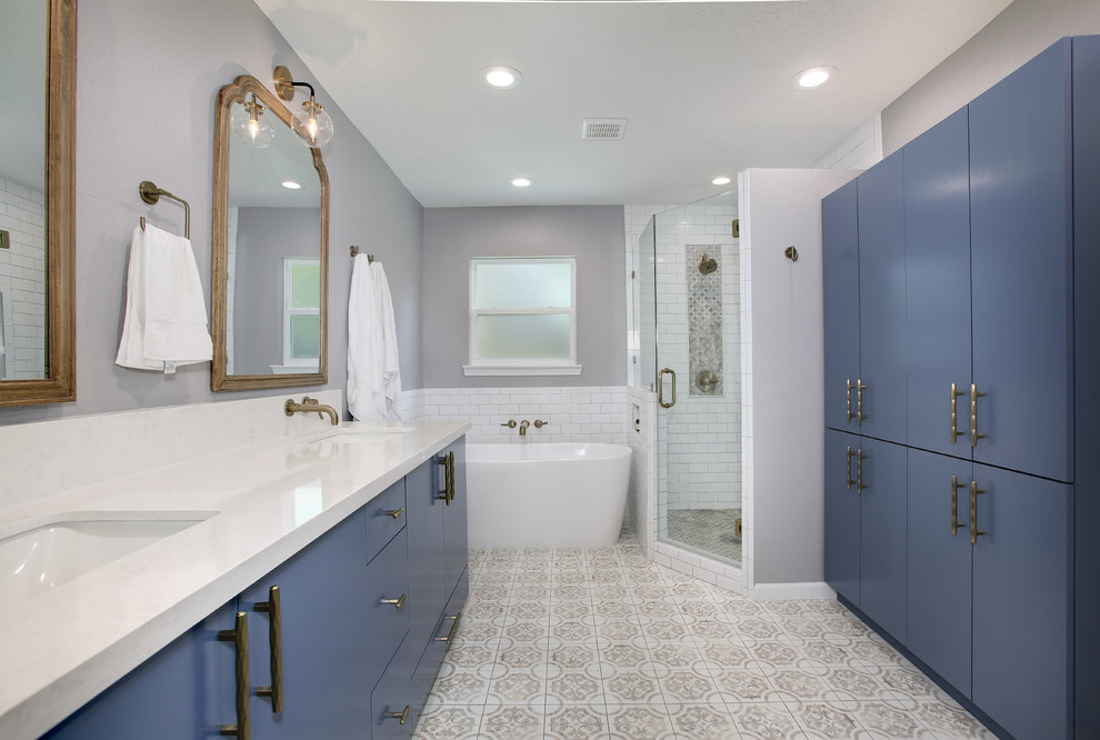 Источник вдохновения для домашнего уюта: большая главная ванная комната в стиле фьюжн с плоскими фасадами, синими фасадами, отдельно стоящей ванной, угловым душем, раздельным унитазом, белой плиткой, плиткой кабанчик, серыми стенами, полом из терракотовой плитки, врезной раковиной, столешницей из искусственного кварца, бежевым полом, душем с распашными дверями и белой столешницей