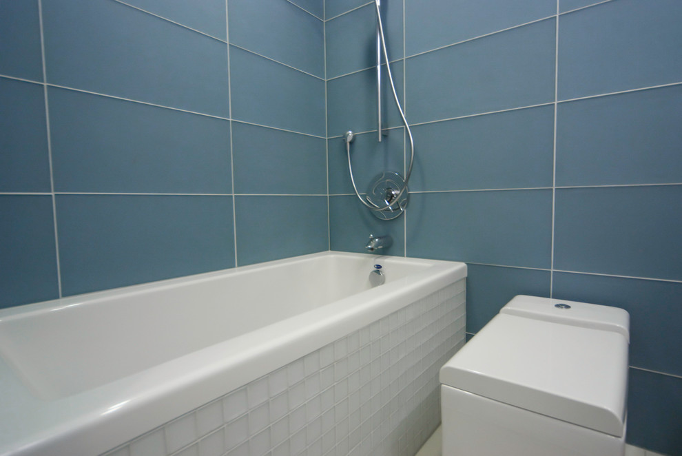 Idée de décoration pour une petite salle de bain principale minimaliste en bois clair avec une baignoire en alcôve, WC à poser, un carrelage bleu, un carrelage en pâte de verre, sol en béton ciré, un placard sans porte, un mur rose, un lavabo intégré et un plan de toilette en béton.