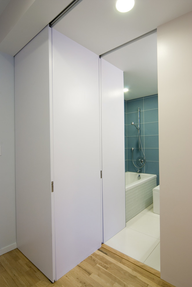 Exempel på ett litet modernt en-suite badrum, med ett badkar i en alkov, glaskakel, betonggolv, öppna hyllor, skåp i ljust trä, en toalettstol med hel cisternkåpa, blå kakel, ett integrerad handfat och bänkskiva i betong