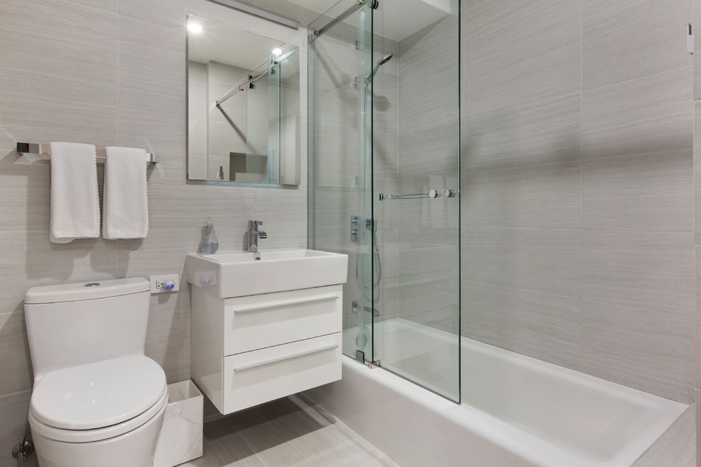 Свежая идея для дизайна: главная ванная комната среднего размера в современном стиле с ванной в нише, душем над ванной, мраморным полом, душем с раздвижными дверями, плоскими фасадами, белыми фасадами, раздельным унитазом, белой плиткой, мраморной плиткой, серыми стенами, консольной раковиной и белым полом - отличное фото интерьера