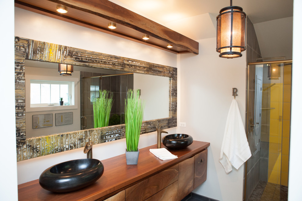 Asiatisk inredning av ett mellanstort en-suite badrum, med släta luckor, skåp i mellenmörkt trä, ett fristående badkar, en dusch i en alkov, en toalettstol med separat cisternkåpa, grå kakel, vita väggar, ett fristående handfat och träbänkskiva