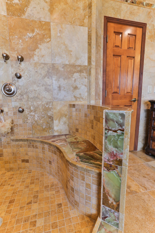 На фото: большая главная ванная комната в средиземноморском стиле с врезной раковиной, фасадами островного типа, фасадами цвета дерева среднего тона, накладной ванной, угловым душем, бежевой плиткой, каменной плиткой и полом из травертина