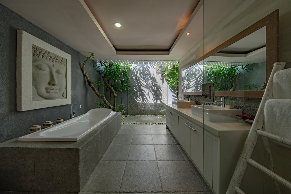 Exempel på ett mellanstort asiatiskt vit vitt en-suite badrum, med luckor med infälld panel, skåp i mörkt trä, ett platsbyggt badkar, en dubbeldusch, grå kakel, keramikplattor, grå väggar, cementgolv, ett nedsänkt handfat, granitbänkskiva, vitt golv och med dusch som är öppen
