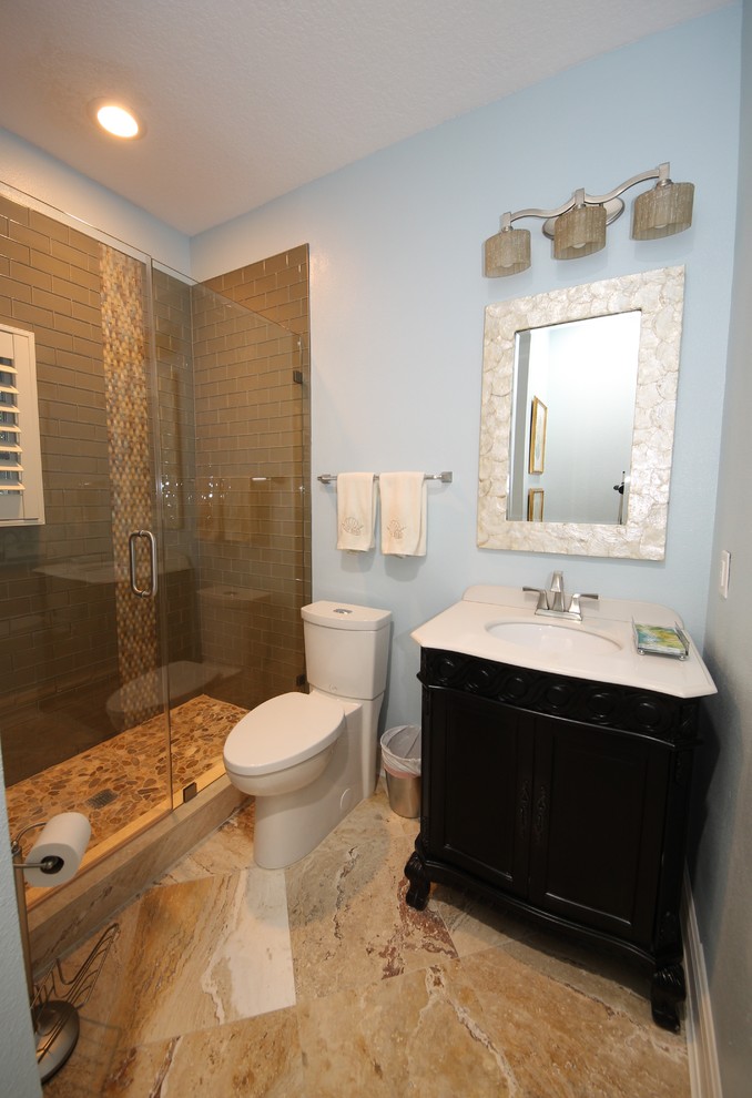 Inspiration för små klassiska badrum, med möbel-liknande, svarta skåp, bänkskiva i akrylsten, brun kakel, stenkakel, en dusch i en alkov, en toalettstol med hel cisternkåpa, ett integrerad handfat, blå väggar och travertin golv