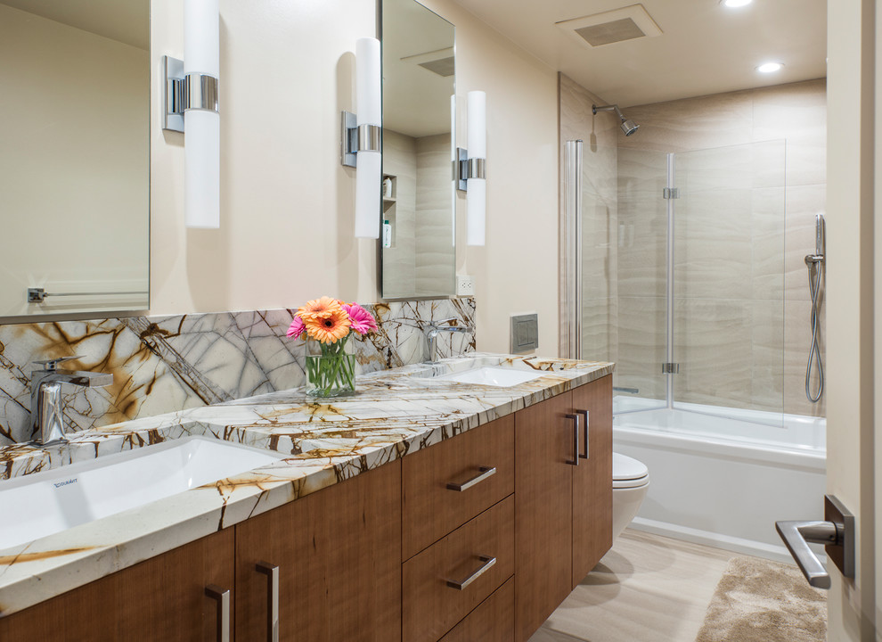 Example of a mid-sized trendy 3/4 beige tile and ceramic tile ceramic tile and beige floor bathroom design in Seattle with flat-panel cabinets, medium tone wood cabinets, a one-piece toilet, beige walls, an undermount sink, quartzite countertops and a hinged shower door