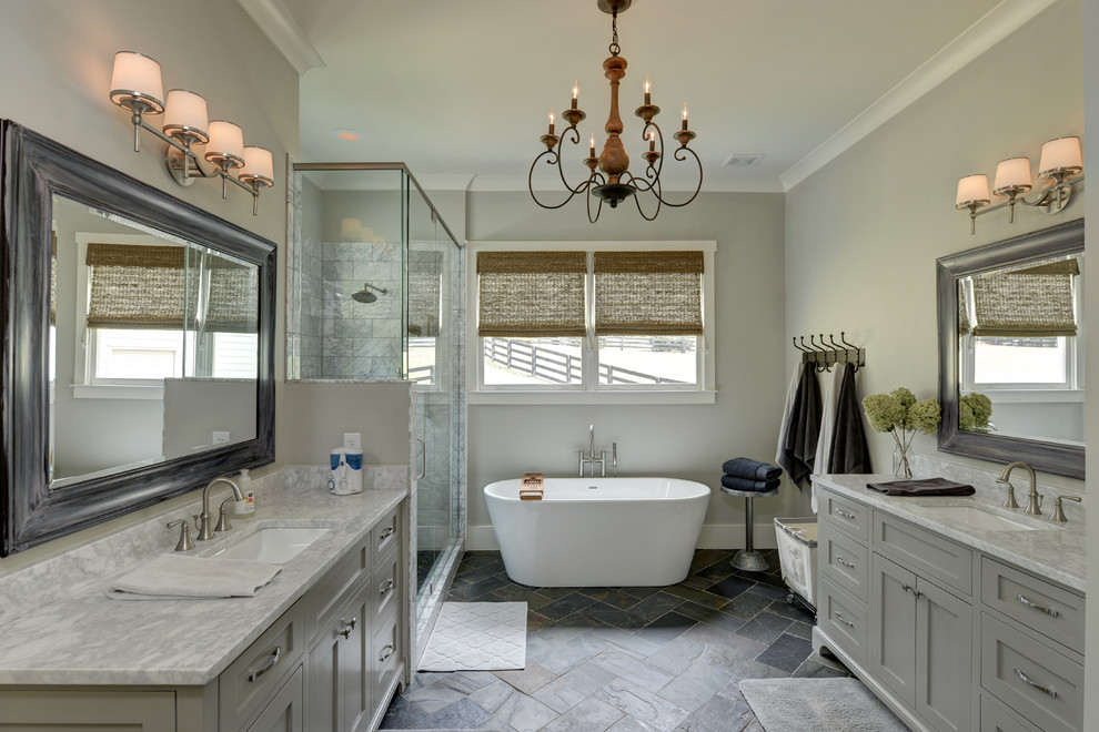 На фото: главная ванная комната в стиле кантри с фасадами в стиле шейкер, серыми фасадами, отдельно стоящей ванной, угловым душем, серыми стенами, врезной раковиной, серым полом, душем с распашными дверями и серой столешницей с