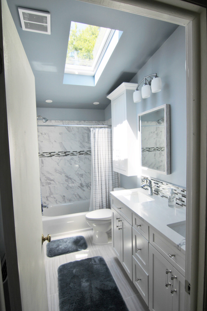 This is an example of a medium sized traditional ensuite bathroom in Baltimore with recessed-panel cabinets, white cabinets, an alcove bath, a shower/bath combination, a two-piece toilet, black and white tiles, ceramic tiles, blue walls, ceramic flooring, a submerged sink, granite worktops, grey floors, a shower curtain, white worktops, double sinks, a built in vanity unit and a vaulted ceiling.