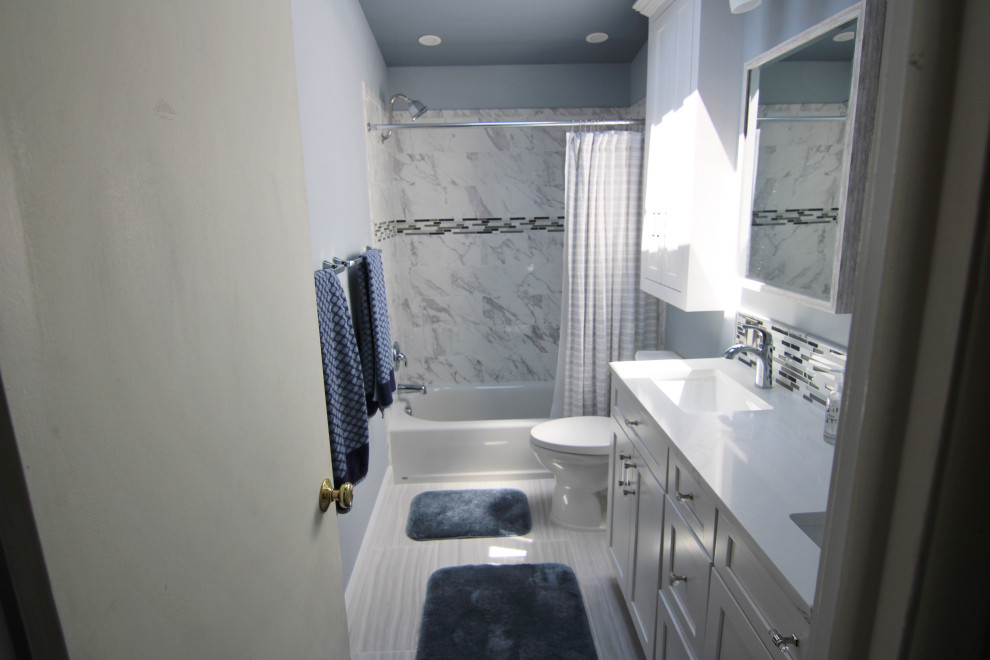 Design ideas for a medium sized traditional ensuite bathroom in Baltimore with recessed-panel cabinets, white cabinets, an alcove bath, a shower/bath combination, a two-piece toilet, black and white tiles, ceramic tiles, blue walls, ceramic flooring, a submerged sink, granite worktops, grey floors, a shower curtain, white worktops, double sinks, a built in vanity unit and a vaulted ceiling.