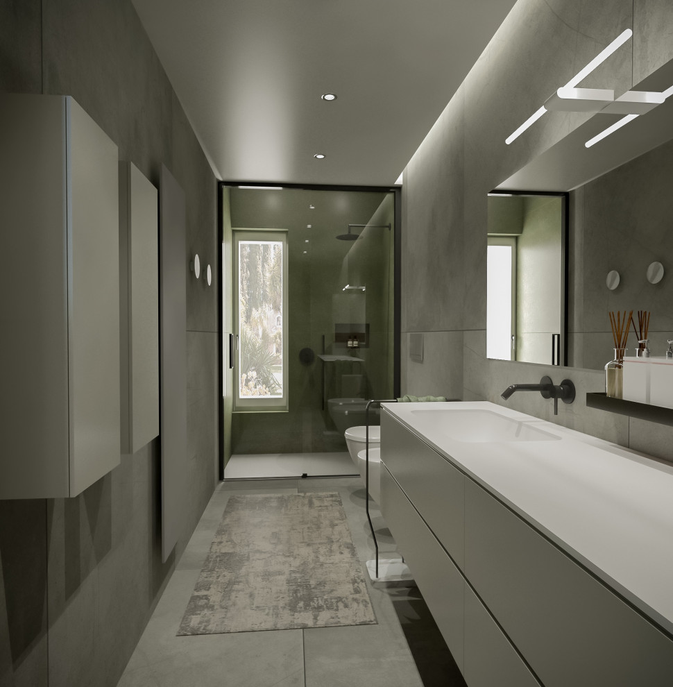 Foto på ett stort funkis grå badrum med dusch, med släta luckor, grå skåp, en dusch i en alkov, en vägghängd toalettstol, grå kakel, porslinskakel, grå väggar, klinkergolv i porslin, ett nedsänkt handfat, bänkskiva i akrylsten, grått golv och dusch med skjutdörr