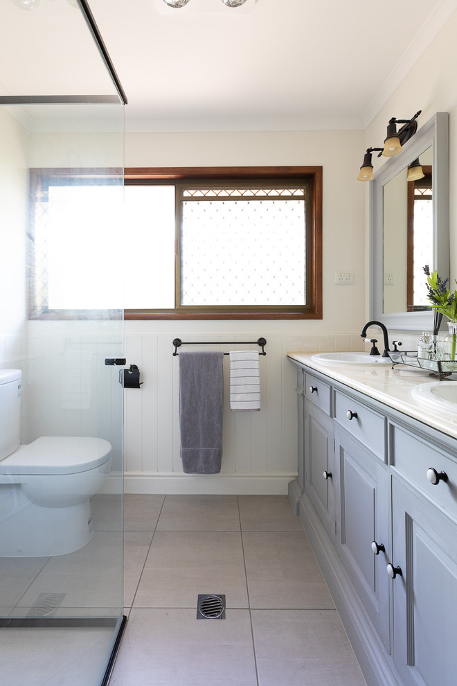 Exempel på ett klassiskt beige beige badrum med dusch, med luckor med upphöjd panel, grå skåp, en hörndusch, beige väggar, ett nedsänkt handfat och beiget golv