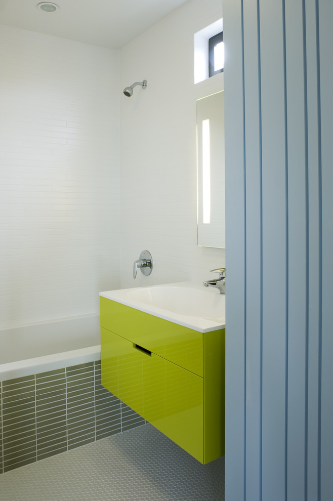 Modelo de cuarto de baño infantil minimalista con lavabo integrado, armarios con paneles lisos, puertas de armario verdes y combinación de ducha y bañera