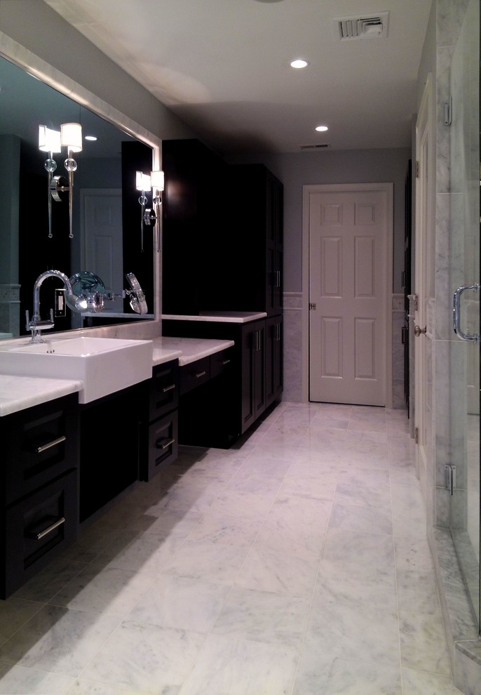 Cette photo montre une grande salle de bain principale tendance en bois foncé avec une grande vasque, un placard avec porte à panneau encastré, un plan de toilette en marbre, une baignoire indépendante, une douche d'angle, WC à poser, un carrelage blanc, un carrelage de pierre, un mur gris, un sol en marbre, un sol blanc et une cabine de douche à porte battante.