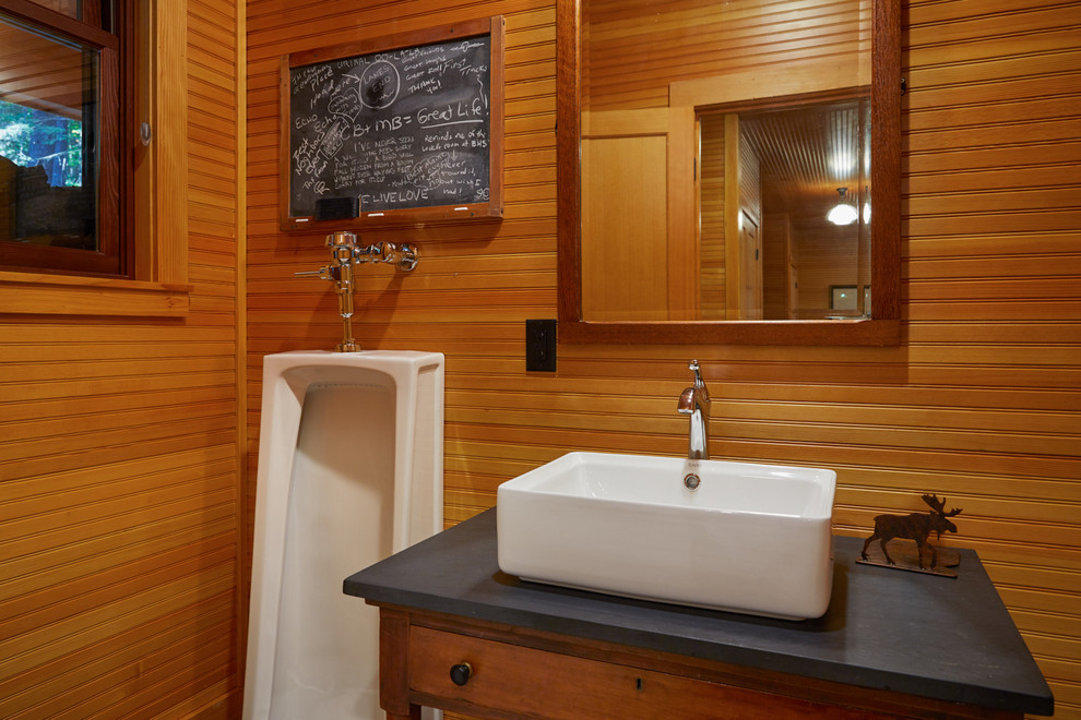 Exemple d'une grande salle de bain principale montagne en bois clair avec un urinoir, une vasque, un placard avec porte à panneau surélevé, une baignoire d'angle, une douche ouverte, un carrelage gris, un carrelage de pierre, un mur beige, un sol en carrelage de céramique et un plan de toilette en surface solide.
