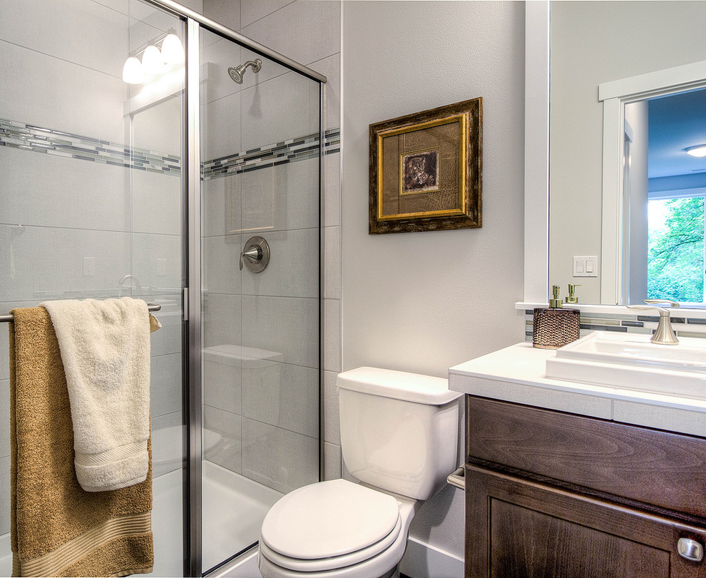 Exempel på ett klassiskt badrum med dusch, med skåp i shakerstil, skåp i mörkt trä, en dusch i en alkov, en toalettstol med separat cisternkåpa, grå kakel, glaskakel, grå väggar, ett nedsänkt handfat, kaklad bänkskiva och dusch med gångjärnsdörr