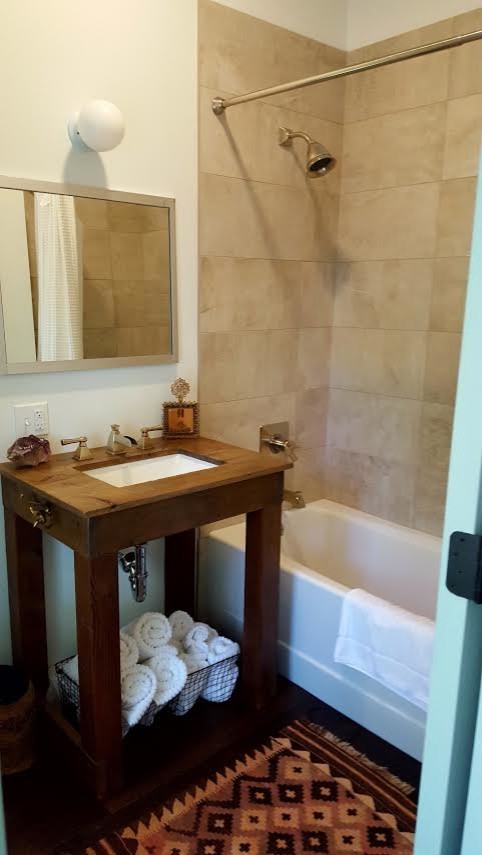 Exemple d'une salle d'eau éclectique en bois foncé de taille moyenne avec un placard sans porte, une baignoire en alcôve, un combiné douche/baignoire, un carrelage beige, des carreaux de céramique, un mur blanc, un lavabo encastré, un plan de toilette en bois et une cabine de douche avec un rideau.